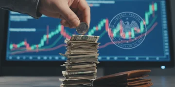Hand placing quarter on dollar bills, symbolizing Federal Reserve rate hike impact on personal finances